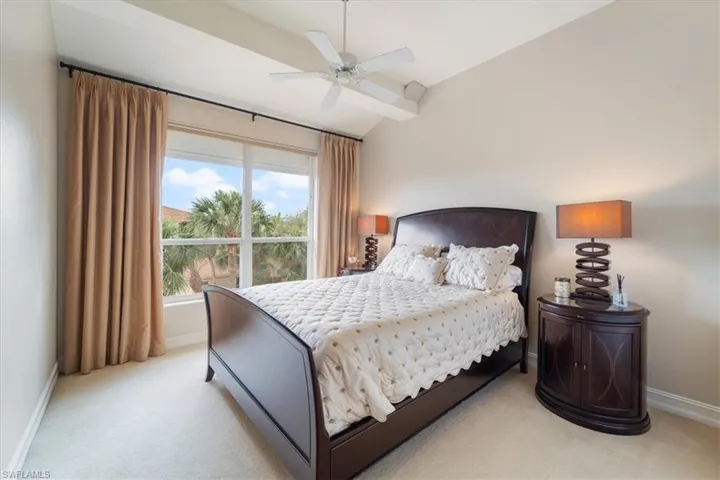 Bedroom featuring a ceiling fan, lofted ceiling, light colored carpet, and baseboards