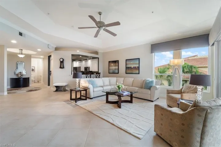 Living room featuring a tray ceiling, light tile patterned floors, recessed lighting, visible vents, and ceiling fan