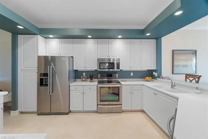 Kitchen featuring recessed lighting, white cabinetry, light countertops, ornamental molding, and appliances with stainless steel finishes