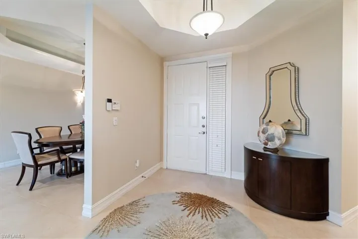 Foyer with light tile patterned flooring and baseboards