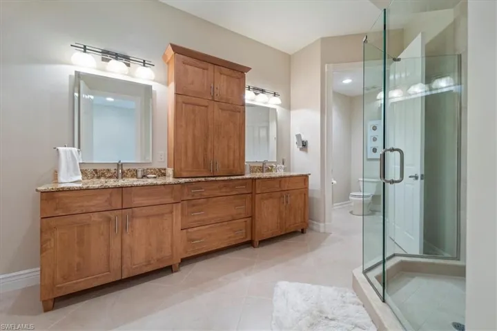 Full bathroom featuring a sink, a shower stall, toilet, and double vanity