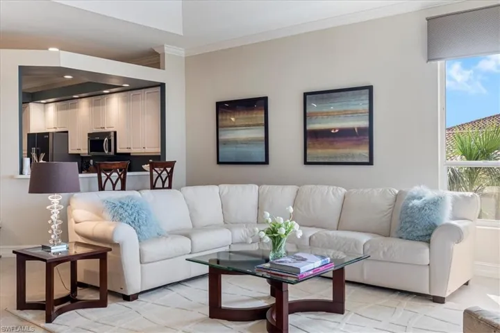 Living area with baseboards, ornamental molding, recessed lighting, and a healthy amount of sunlight