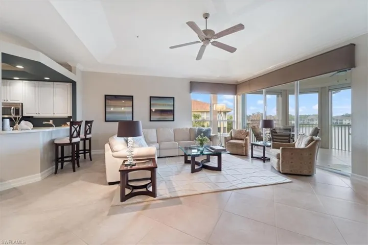 Living area featuring plenty of natural light, a tray ceiling, baseboards, and light tile patterned flooring