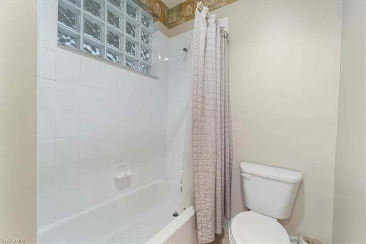 Bathroom with shower / bath combo with shower curtain and toilet