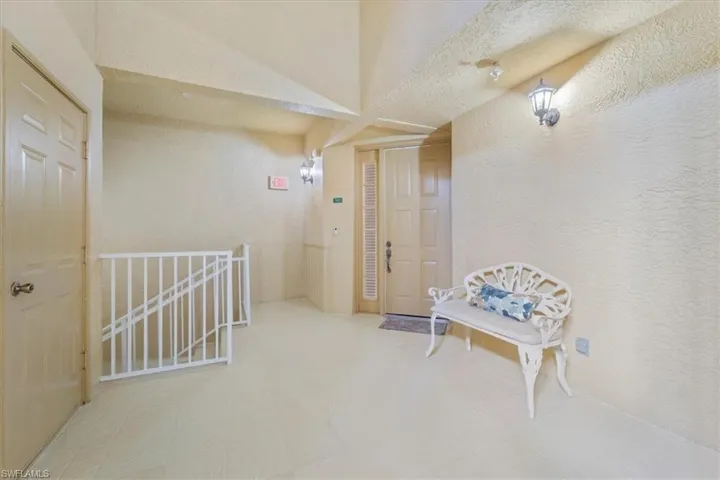 Hallway featuring a textured wall and an upstairs landing