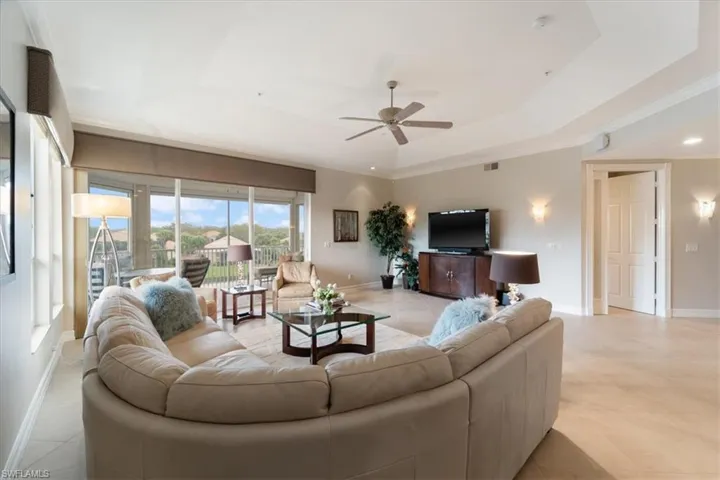 Living room with ceiling fan, a raised ceiling, visible vents, and baseboards