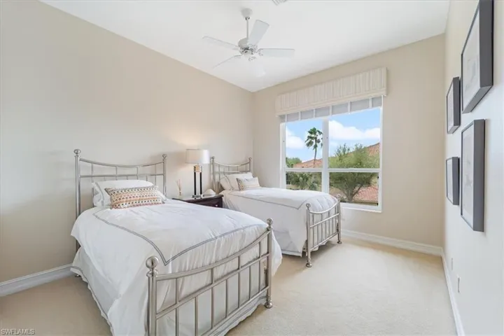 Bedroom with light carpet, ceiling fan, and baseboards
