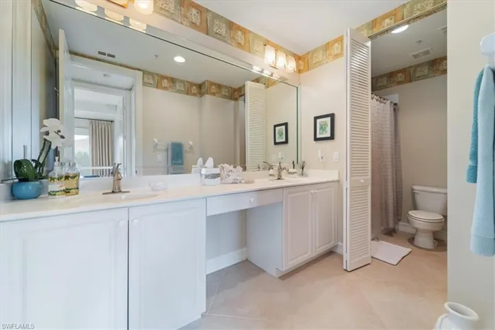 Bathroom with visible vents, double vanity, a sink, and toilet