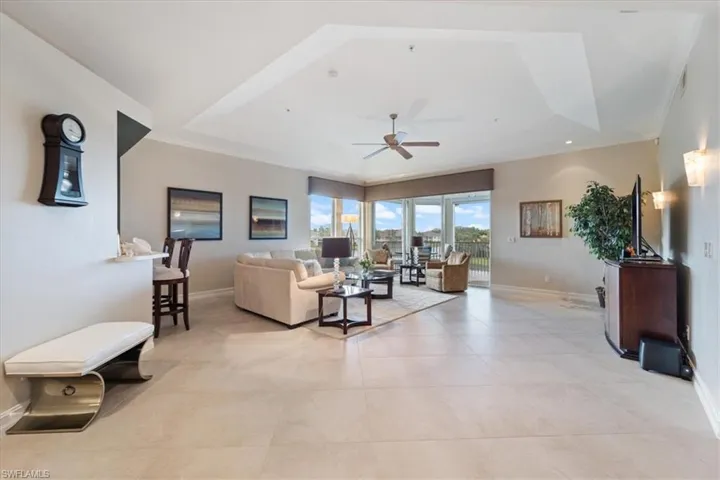 Living room with ceiling fan, crown molding, a raised ceiling, and baseboards