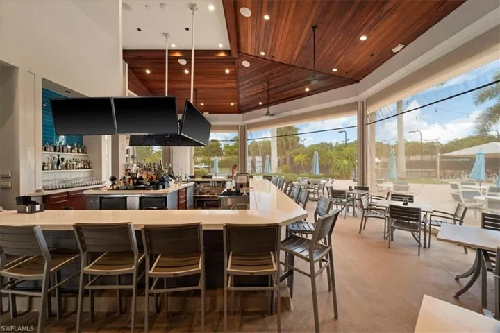 Kitchen with a high ceiling, a kitchen breakfast bar, wood ceiling, decorative light fixtures, and light stone countertops