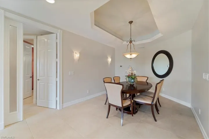 Dining area with light tile patterned floors, baseboards, and a tray ceiling
