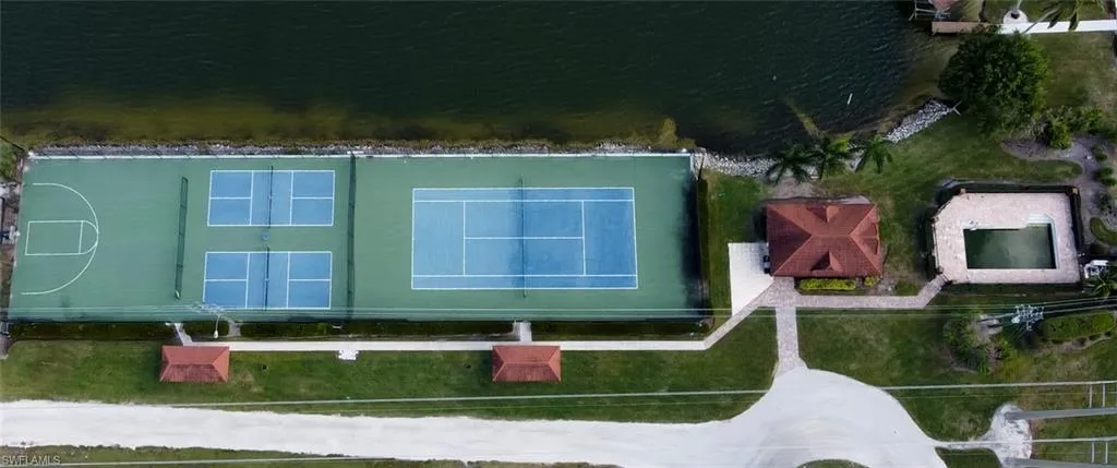 Waterfront recreational area featuring multiple sports courts, a covered pavilion, and an outdoor swimming pool