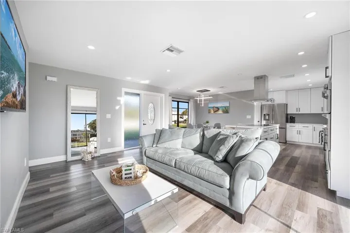 Living area with dark wood-style floors, visible vents, recessed lighting, and baseboards