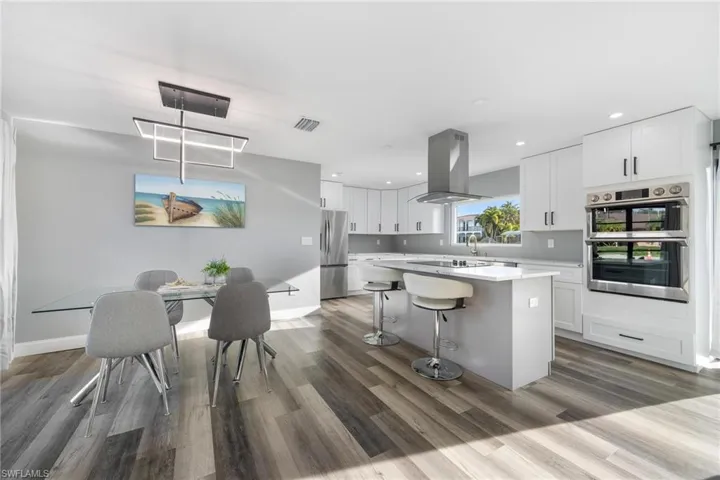 Kitchen with a kitchen island, light countertops, island range hood, white cabinets, and stainless steel appliances