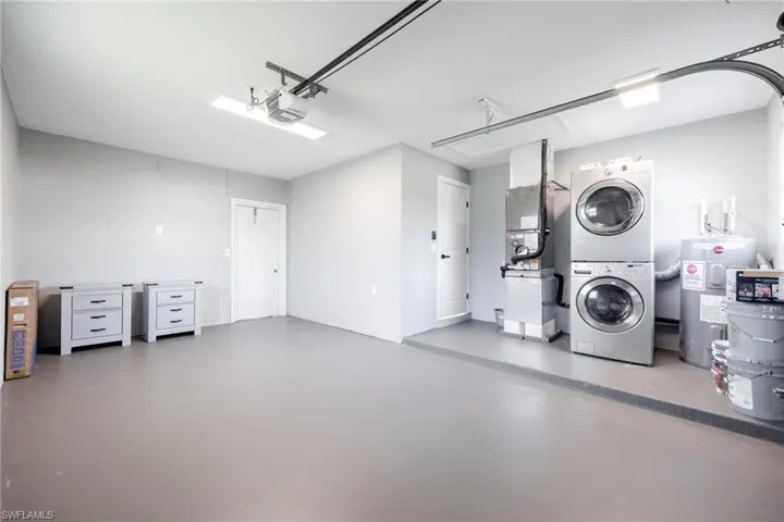 Garage with stacked washer and dryer, a garage door opener, and electric water heater