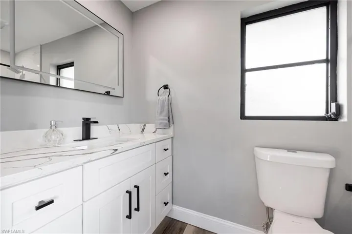 Bathroom featuring vanity, toilet, wood finished floors, and baseboards
