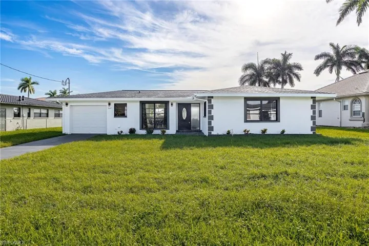 Single story home with a garage, a front lawn, driveway, and stucco siding