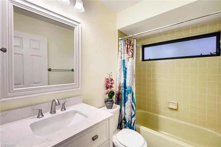 Guest bathroom with updated cabinetry, mirror, light and fixtures.  Tile and tub are in excellent condition!