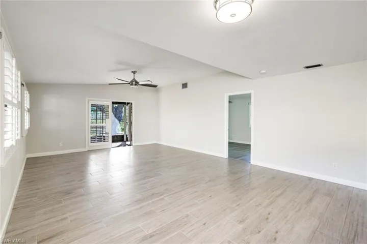 Living area from the kitchen/dining area with sliders to the screened lanai and master bedroom door.