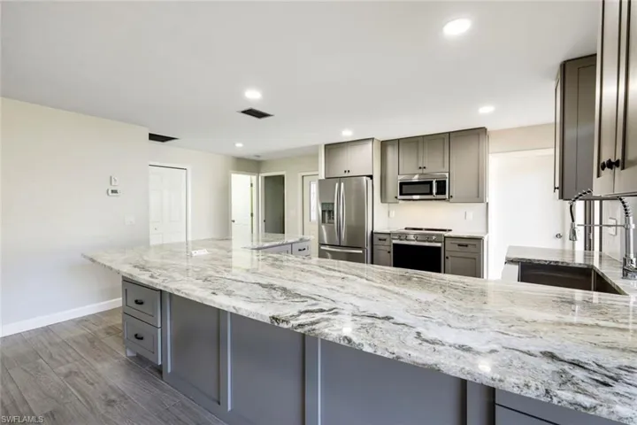 Kitchen offers light gray custom cabinetry with built in pop power in the center of the granite island, stainless sink, upgraded fixtures and stainless steel appliances!  Extra cabinets on both sides of the 4 ft wide island cabinets allows for plenty of extra storage!  Plenty of space for barstools!