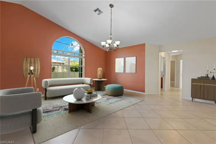Virtually staged - Living room featuring a notable chandelier, lofted ceiling, and light tile flooring