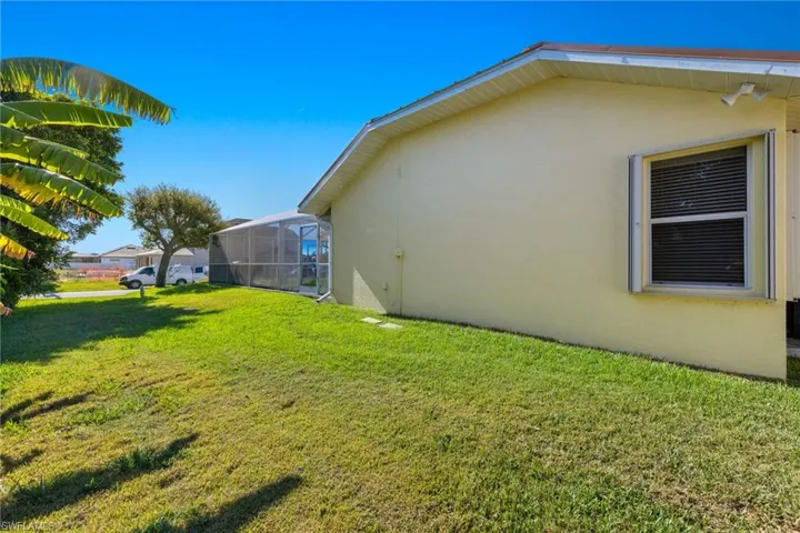 View of side of property with glass enclosure and a yard