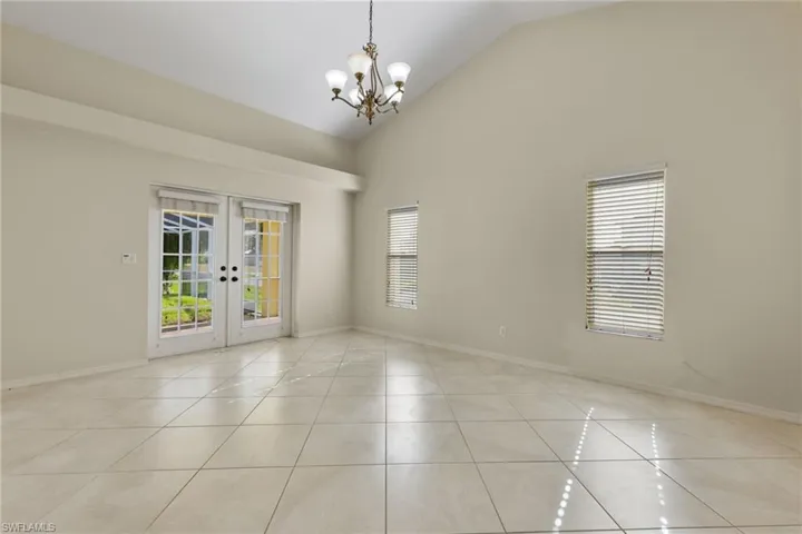 Unfurnished room with a chandelier, french doors, and light tile flooring