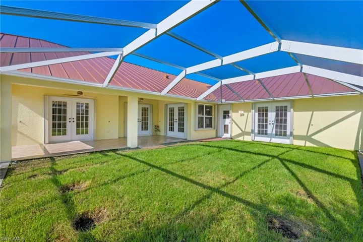 Back of house with french doors, a lawn, and ceiling fan