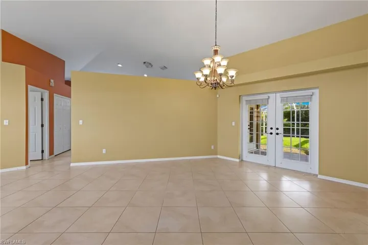 Tiled family room featuring french doors and an inviting chandelier
