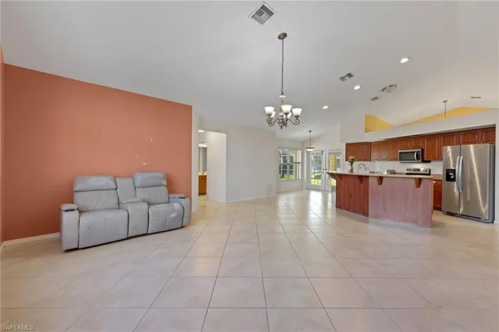 Living room featuring a notable chandelier, vaulted ceiling, and light tile flooring