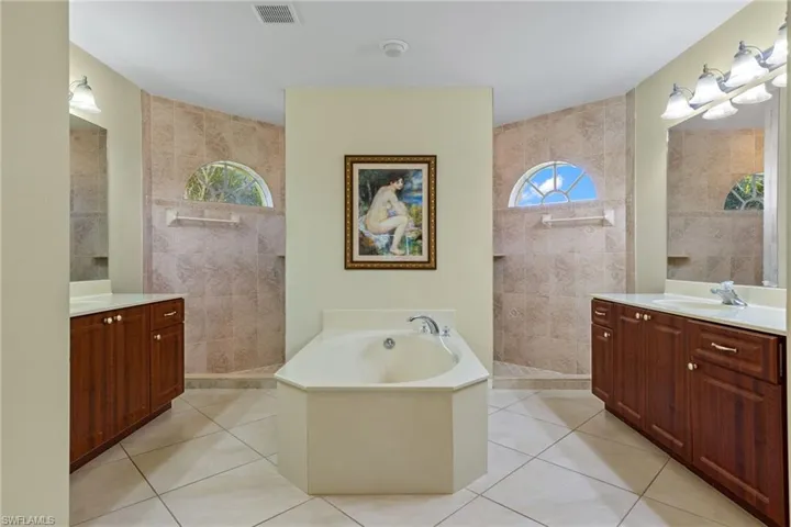 Bathroom with tile walls, tile floors, independent shower and bath, and vanity.