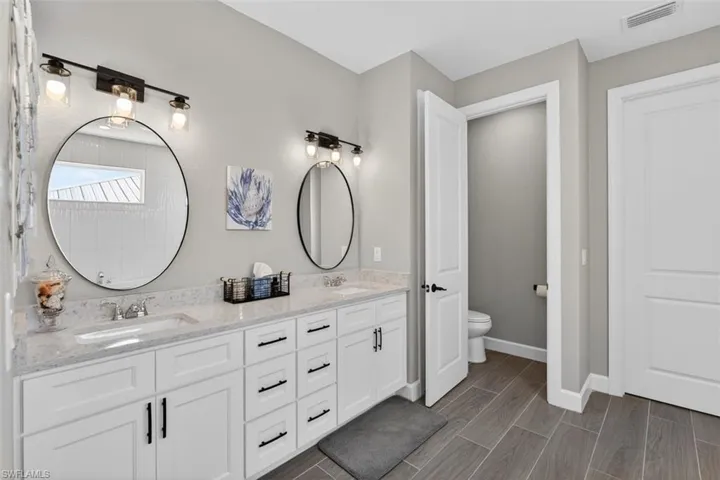 Full bathroom with double vanity and wood finish floors