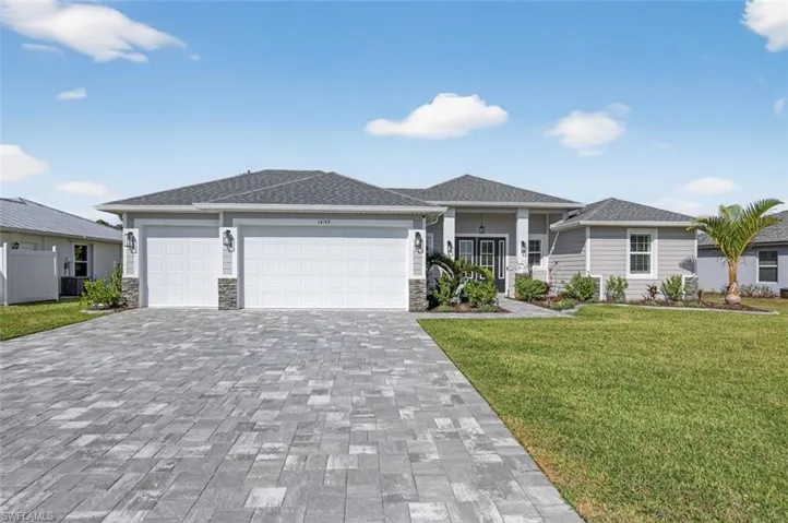 Prairie-style house with stone siding, a front yard, an attached garage, decorative driveway, and a shingled roof