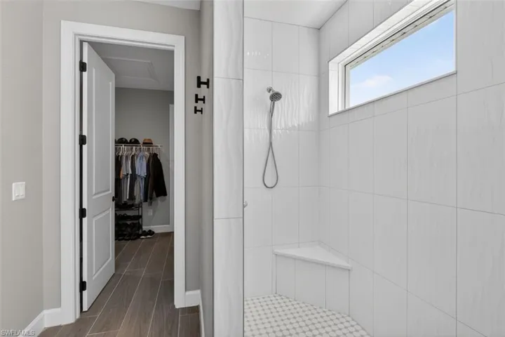 Full bath with tiled shower, wood tiled floors, and a walk in closet