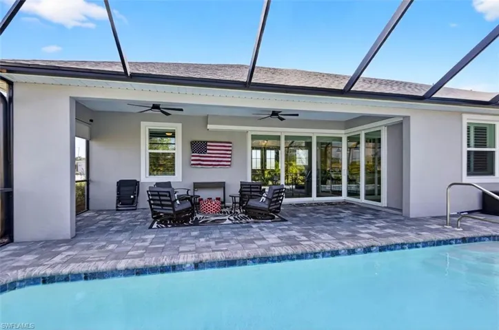 Back of house featuring ceiling fan, stucco siding, an outdoor pool, a sunroom, and a lanai