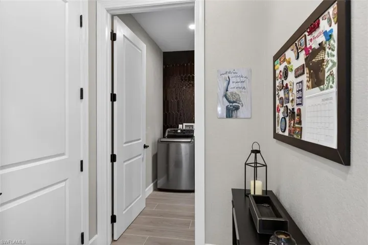 Hall with washer / clothes dryer, wood tiled floors, and a textured wall