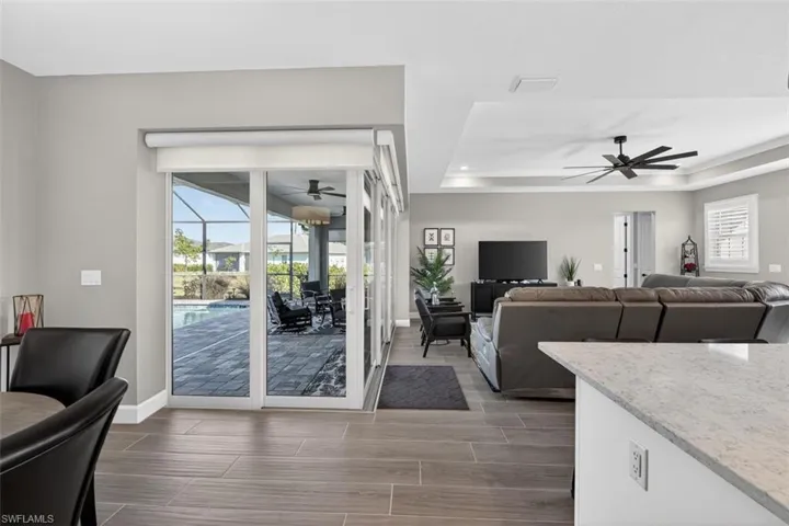 Living area featuring a sunroom, a raised ceiling, wood finish floors, a ceiling fan, and recessed lighting