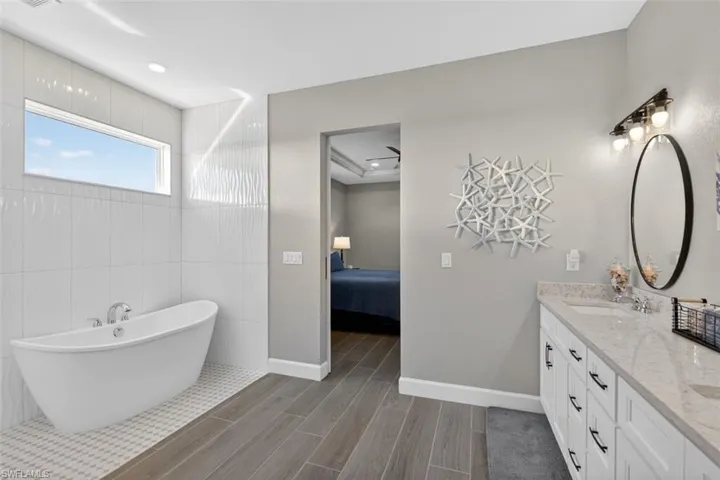 Bathroom with double vanity, wood tiled floors, ensuite bath, a soaking tub, and recessed lighting