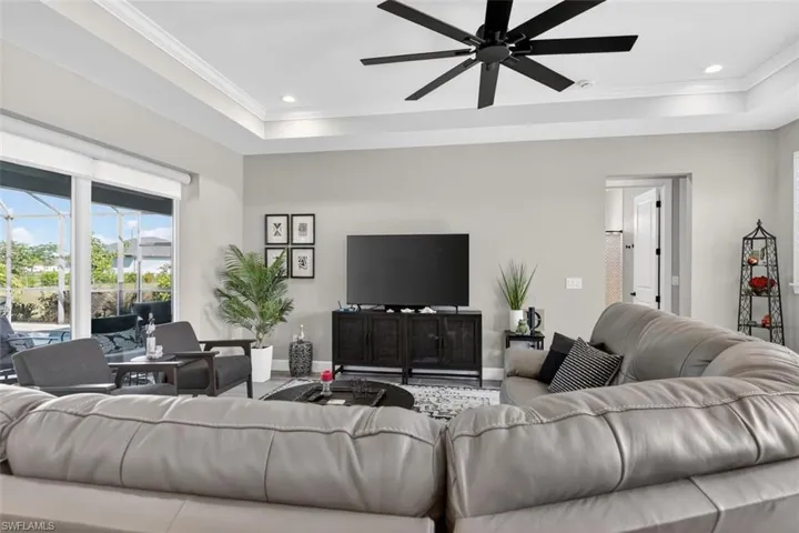 Living room featuring ceiling fan, a raised ceiling, recessed lighting, and crown molding