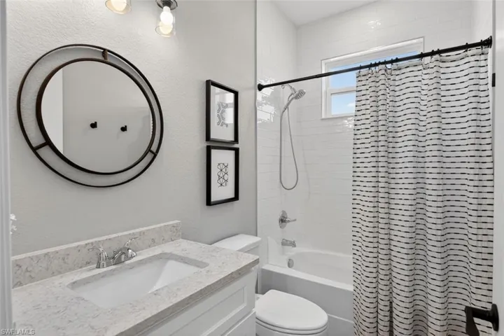 Bathroom featuring vanity, shower / tub combo, and a textured wall