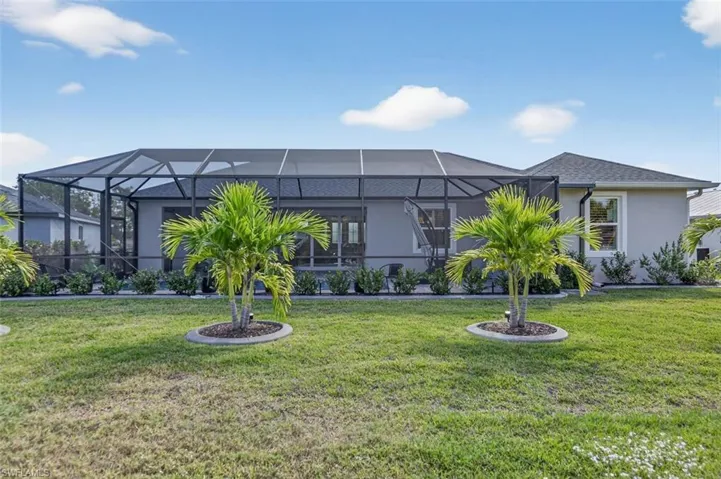 Back of property featuring a lawn, stucco siding, a sunroom, and glass enclosure