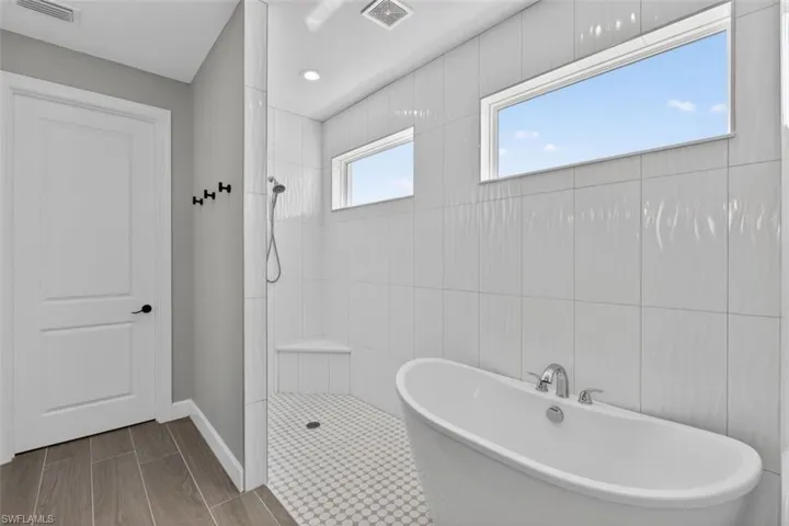 Bathroom with walk in shower, a soaking tub, and wood tiled floors