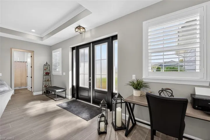 Entryway with wood finish floors, a raised ceiling, ornamental molding, and french doors