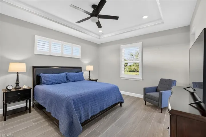 Bedroom featuring wood finish floors, a ceiling fan, recessed lighting, and a raised ceiling