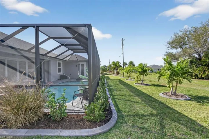 Swimming pool featuring a sunroom, glass enclosure, a lawn, and a patio area