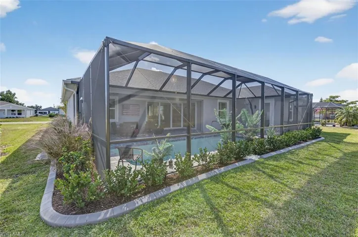 Back of house featuring a sunroom, a yard, a lanai, and stucco siding
