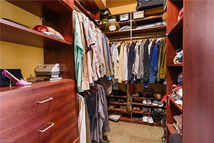 Nicely appointed wood grain walk-in closet with carpet in the owners suite.