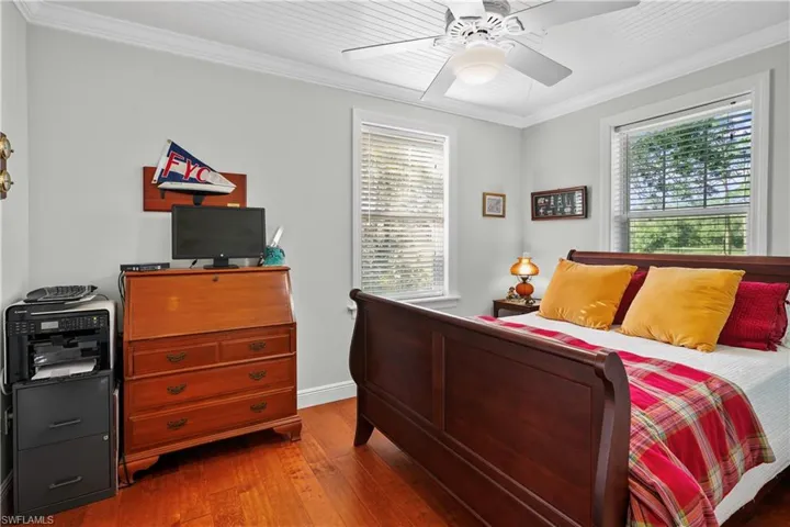Guest bedroom featuring ceiling fan, crown molding, french doors to the screen porch and multiple windows