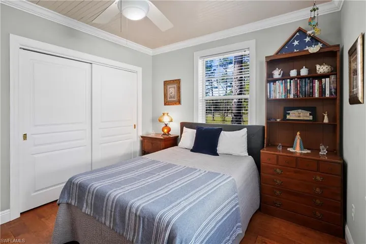 Bedroom with ceiling fan, a closet, crown molding, and dark hardwood / wood-style floors