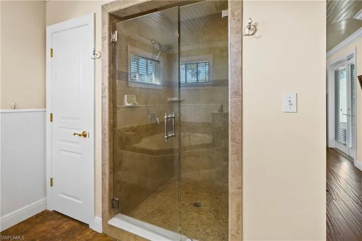 Bathroom in owners suite features a shower with custom glass doors, private water closet.